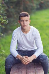 Teenager in sitting on park bench looking up at camera