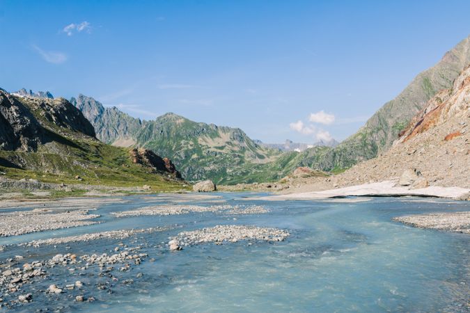 Shallow river flowing along rocky shore in bright day
