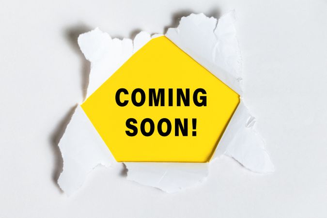 coming soon words text message on torn paper over yellow background