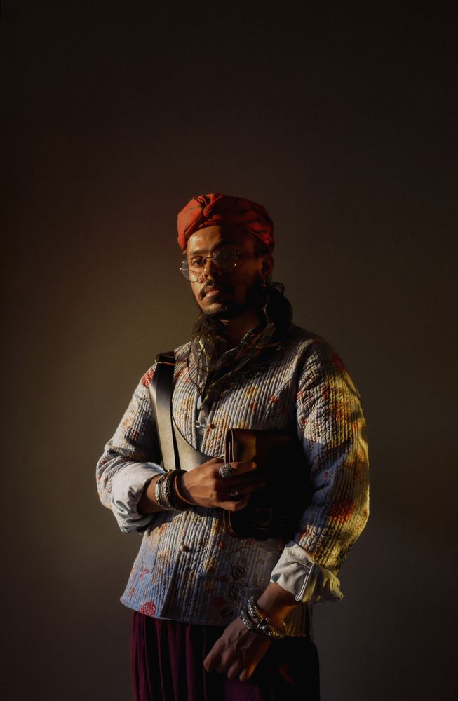 South Asian man standing facing a light