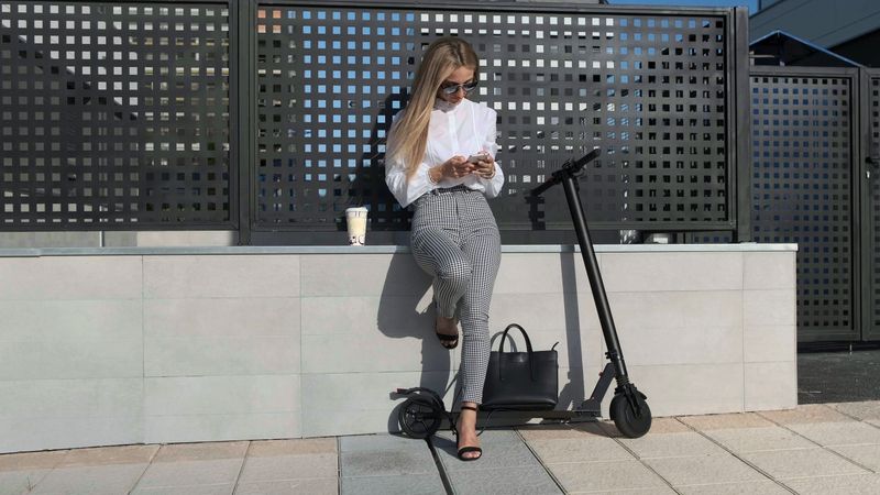 Businesswoman with mobile and her scooter next