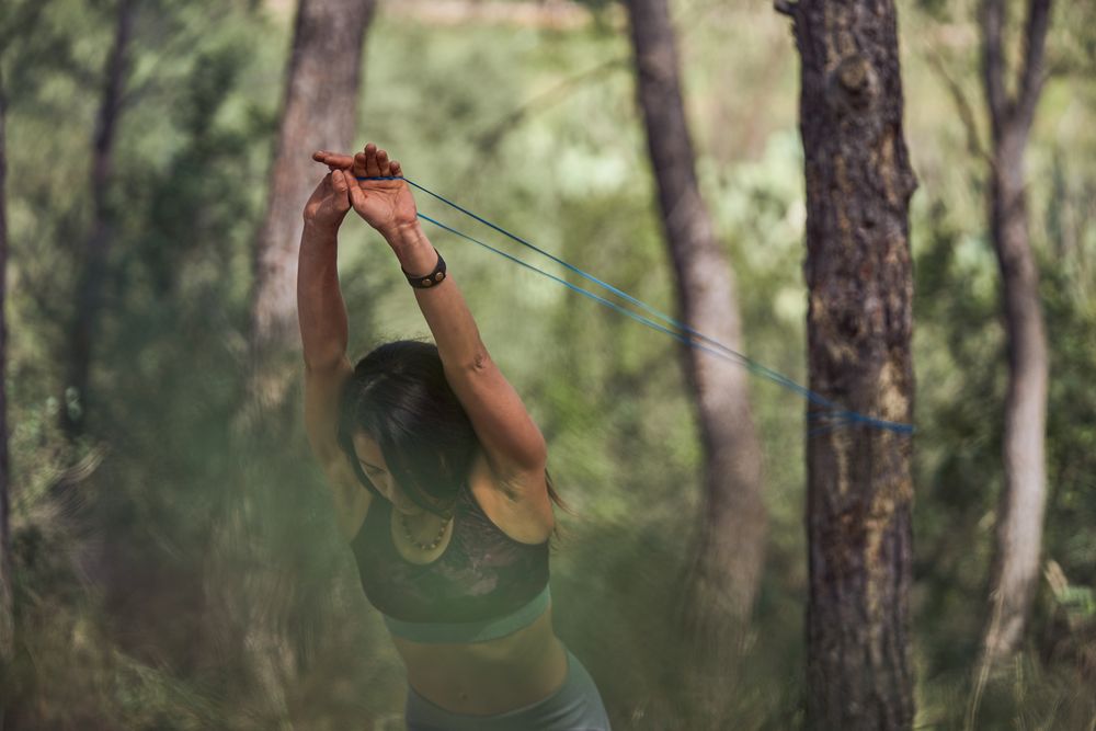Woman stretching resistance band during training in forest