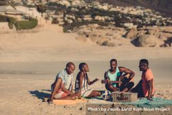 Group of friends with guitar sitting on beach 5nP3Mb