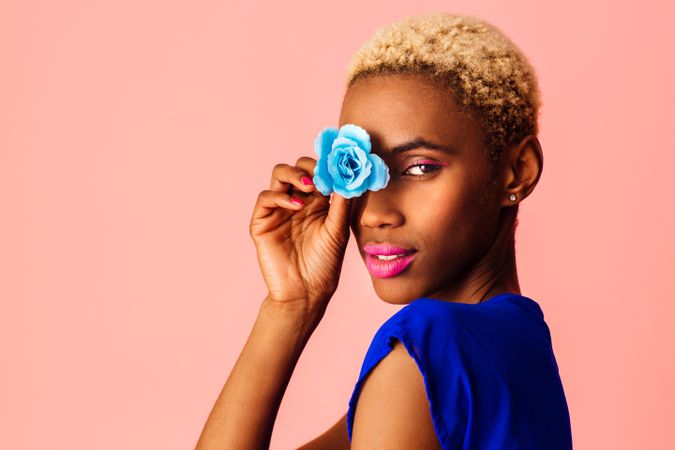 Black woman with short blonde hair with blue flower over her eye