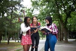 Group of female students looking through textbooks outside