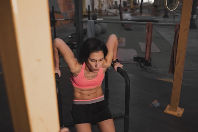 Athletic woman training on parallel bars in gym