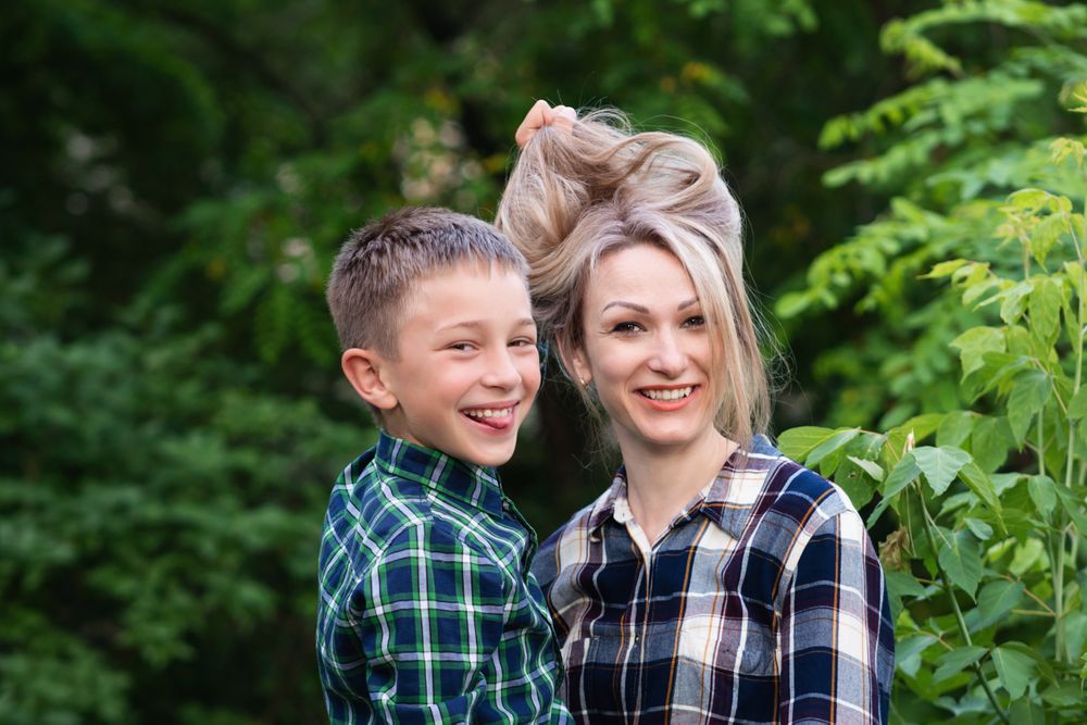 Son playing with mother's hair in backyard