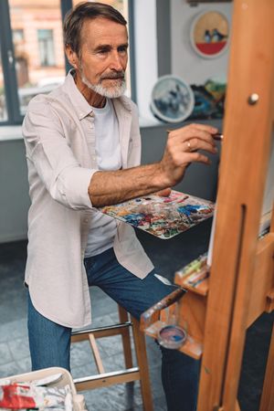 Older man painting on easel