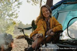 Smiling woman sitting at campsite 47y8O0