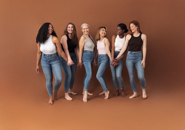 Multi-generational and multi-ethnic women in jeans in brown studio shoot