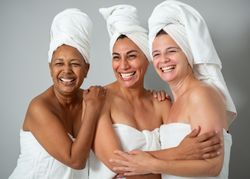 Cheerful multiracial women hugging during spa session