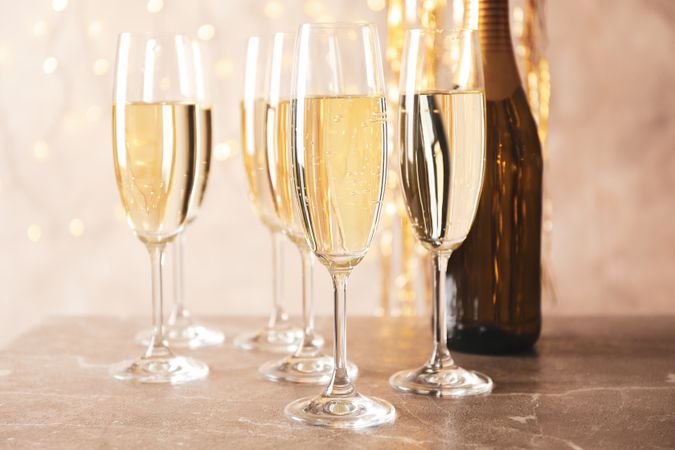 Champagne glasses and bottle against blurred lights background, close up
