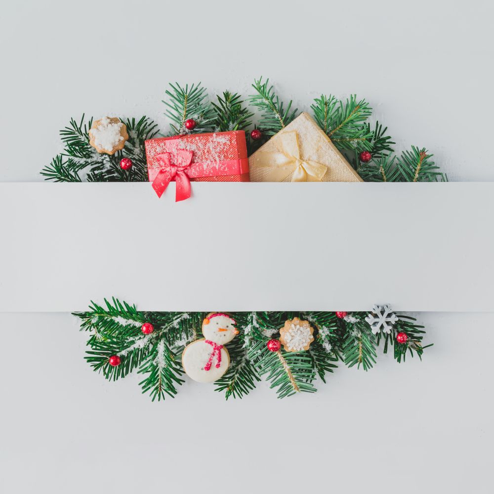 Christmas tree branches with decorations and cookies, behind gray paper
