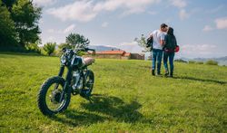 Couple kissing and walking on the field with motorbike
