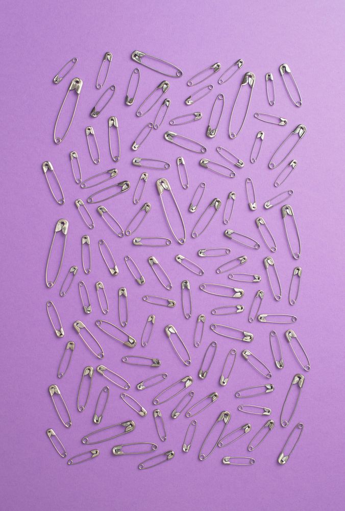 Scattered safety pins on purple background