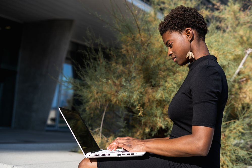 Serious female surfing laptop near modern building