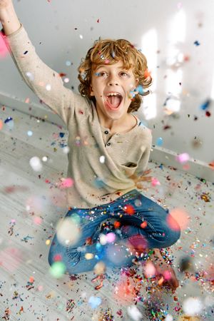 Cheerful boy having fun with confetti