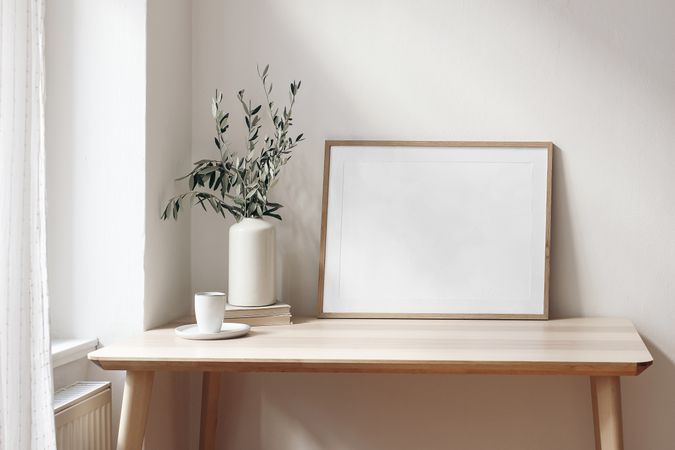Empty horizontal wooden picture frame mockup with cup of coffee on wooden table