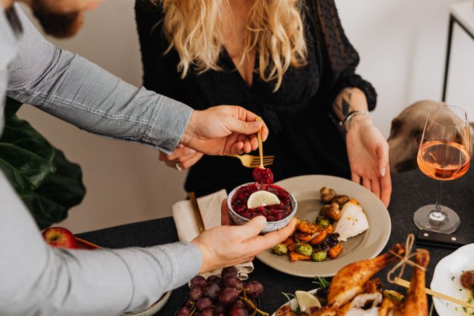 Cropped image of man holding a ramekin of red sauce over dinner table