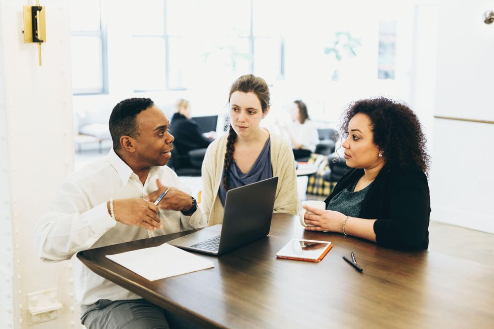 Three colleagues discussing work in an office