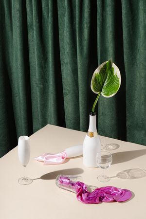 Champagne and glassware in front of green curtain background with pink fabric