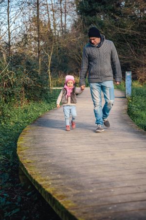 Father in fall coats walking with daughter in forest