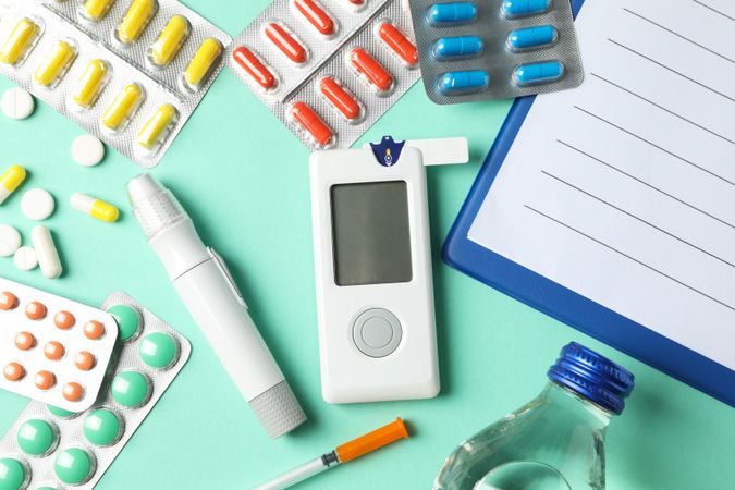 Diabetes accessories on mint background, top view