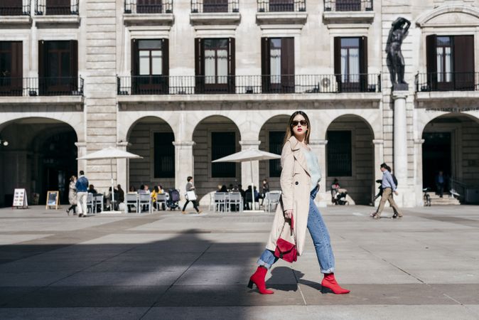 Young happy trendy woman walking in city