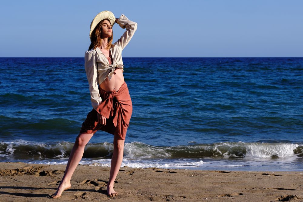 A fashion model with a hat at the beach before sunset