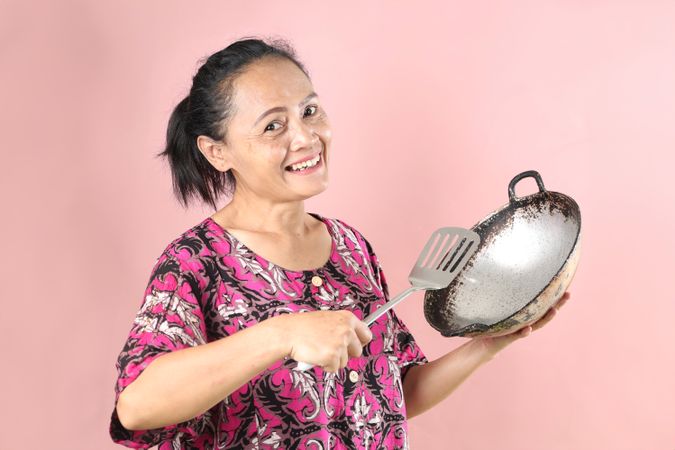 Indonesian Mom Holding Cooking Appliance, Wajan Frying Pan and Slotted Spatula.