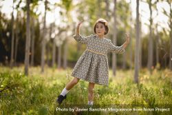 Surprised child standing in dress in nature surrounded by trees 0Vpqj4