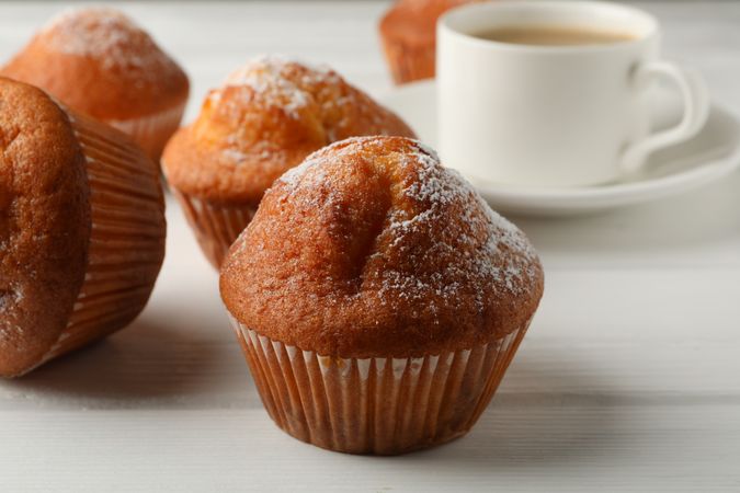 Delicious muffins and cocoa drink on blank wooden background