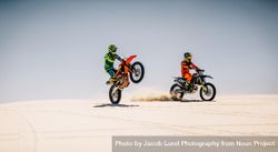 Two motocross riders riding bikes in desert beaw3b