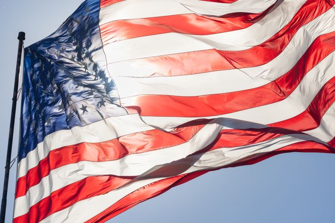 Backlit American Flag Waving In Wind Against a Deep Blue Sky