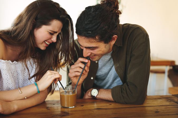 Happy young couple sipping iced coffee together