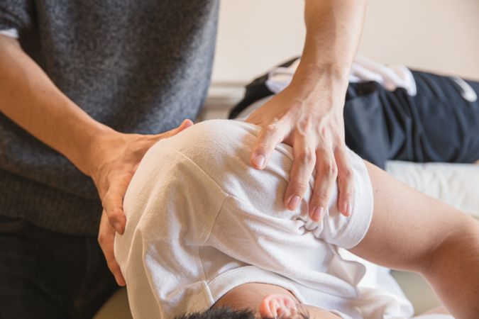 Cropped image of physiotherapist massaging patient's shoulder