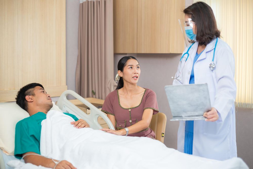 Female with her husband in hospital while doctor visits