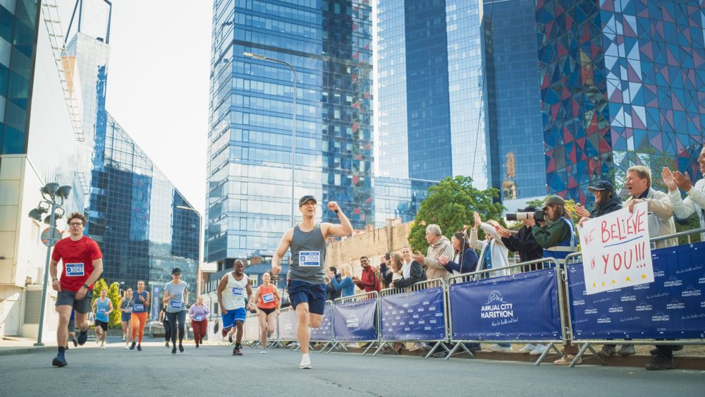 Portrait of Smiling Man Running in a City Marathon, Waving at the Supportive Audience.