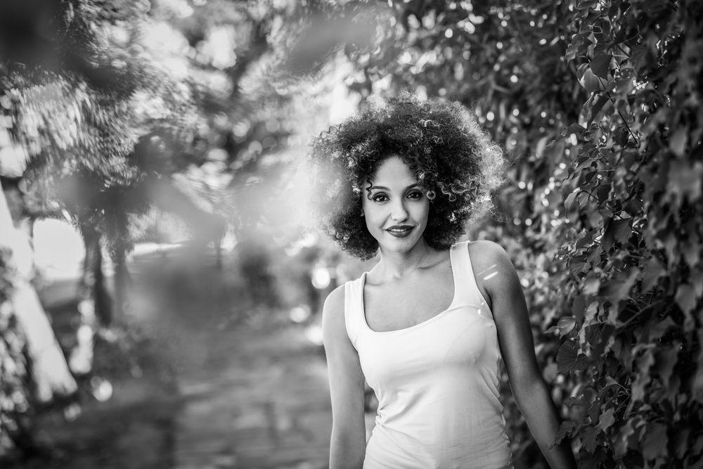 Young Black woman with afro hairstyle smiling in park