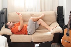 a man relaxing on the sofa looking at his cell phone