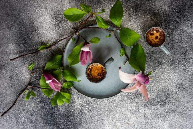 Top view of coffee and magnolia flowers in grey setting