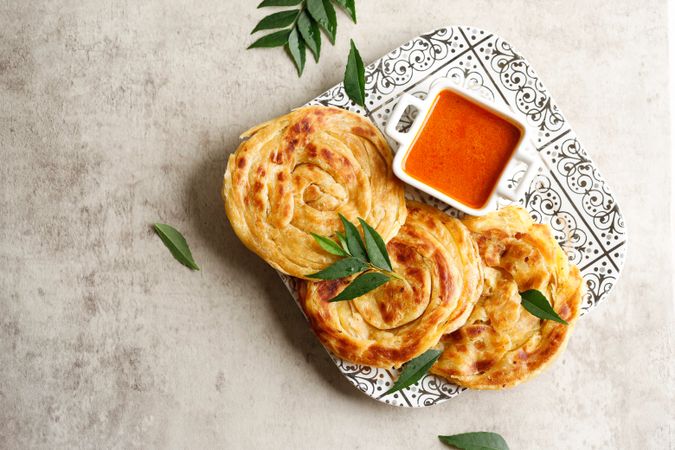 Top view of plate of roti parata or roti canai with dipping sauce