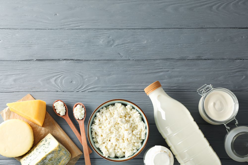 Flat lay. Different dairy products on grey wooden background, copy space