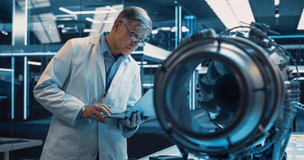 PhD Professor Using Laptop Computer to Develop a High Tech Prototype Electric Motor