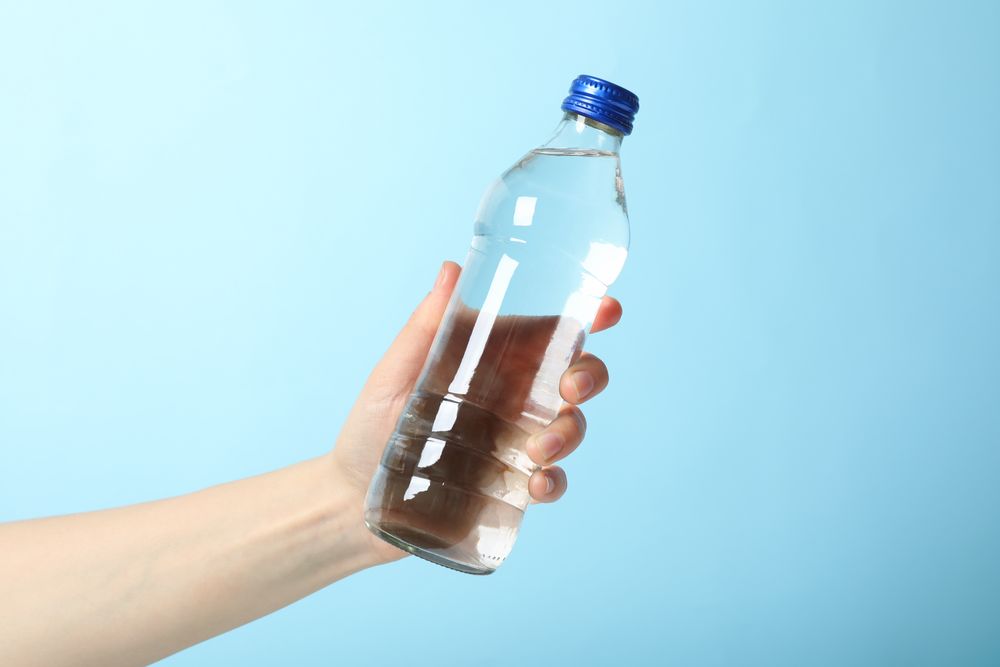 Hand holding plastic water bottle in blue room