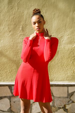 Serious female in casual red dress standing outside