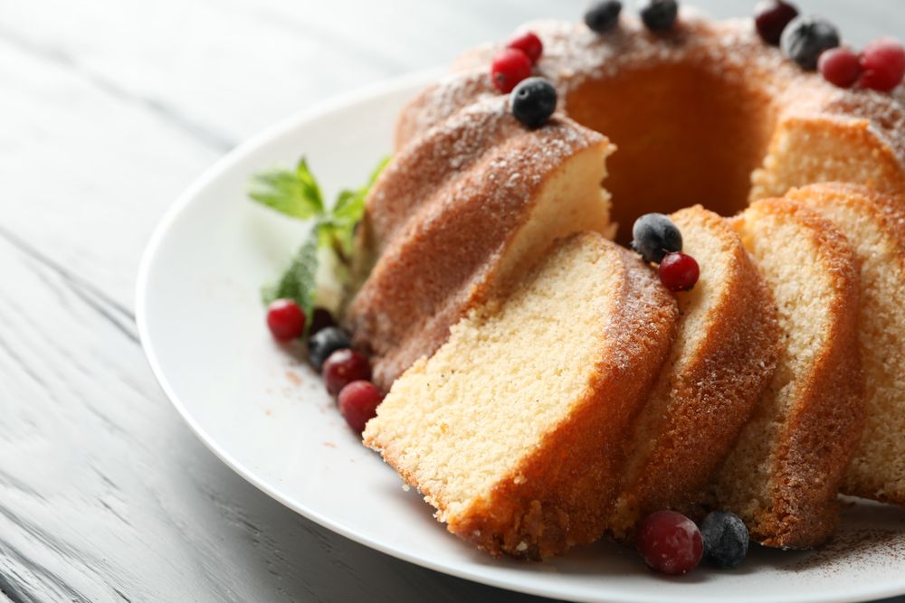 Cake with powdered sugar, berries and mint on wooden background, close up
