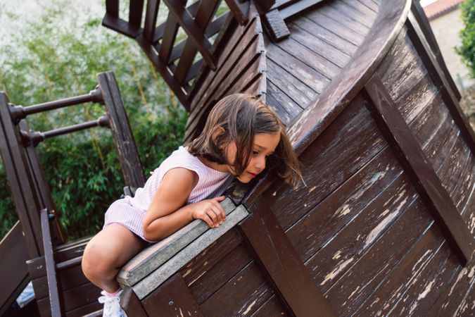 Smiling girl climbing onto wooden playground
