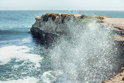 Water with splashes near coast in sunny day