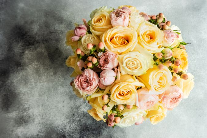 Top view of yellow and pink roses on concrete background with copy space